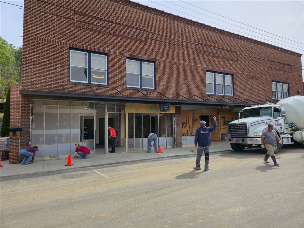 Crews and neighbors rebuilding the Wylie Building storefront, with a cement truck out front