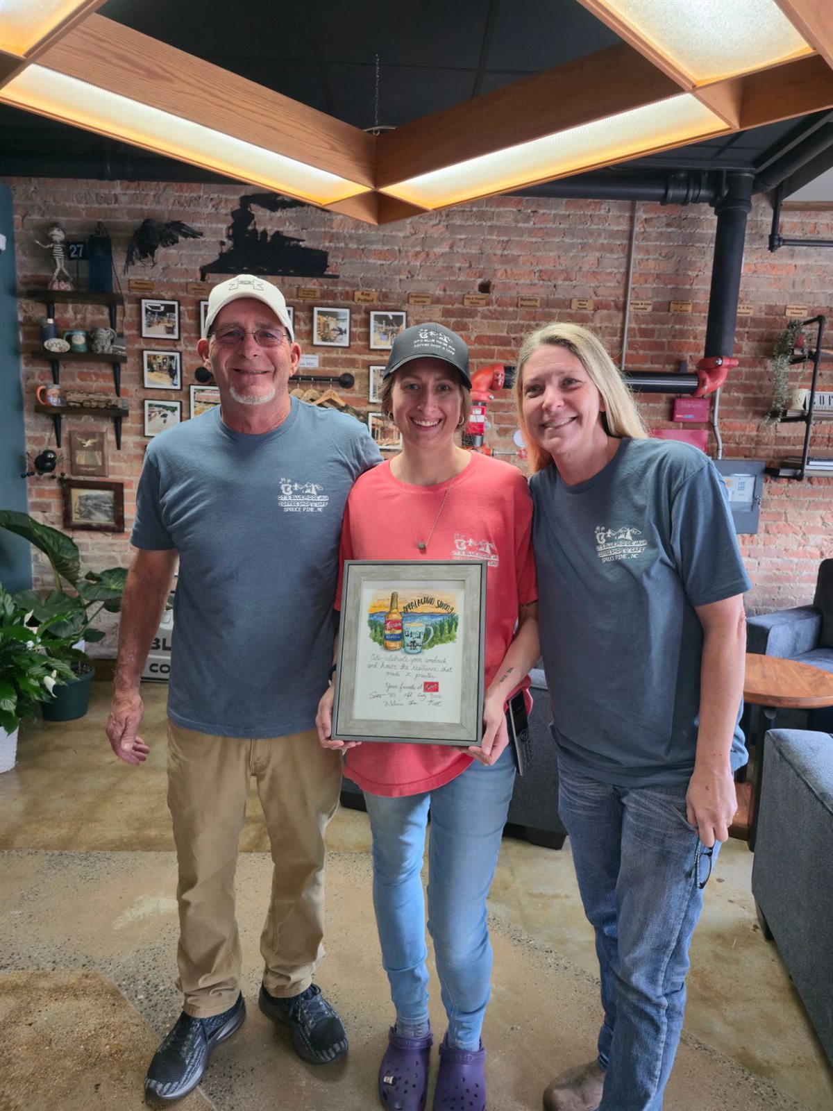 David, Tricia and Taylor inside the rebuilt DT's, holding a framed Appalachian Strong painting