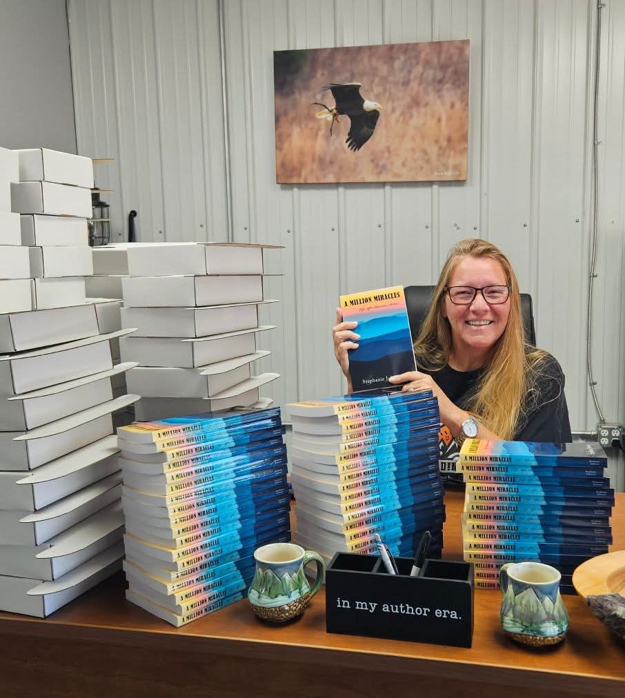 Stephanie Johnson smiling behind stacks of her new book